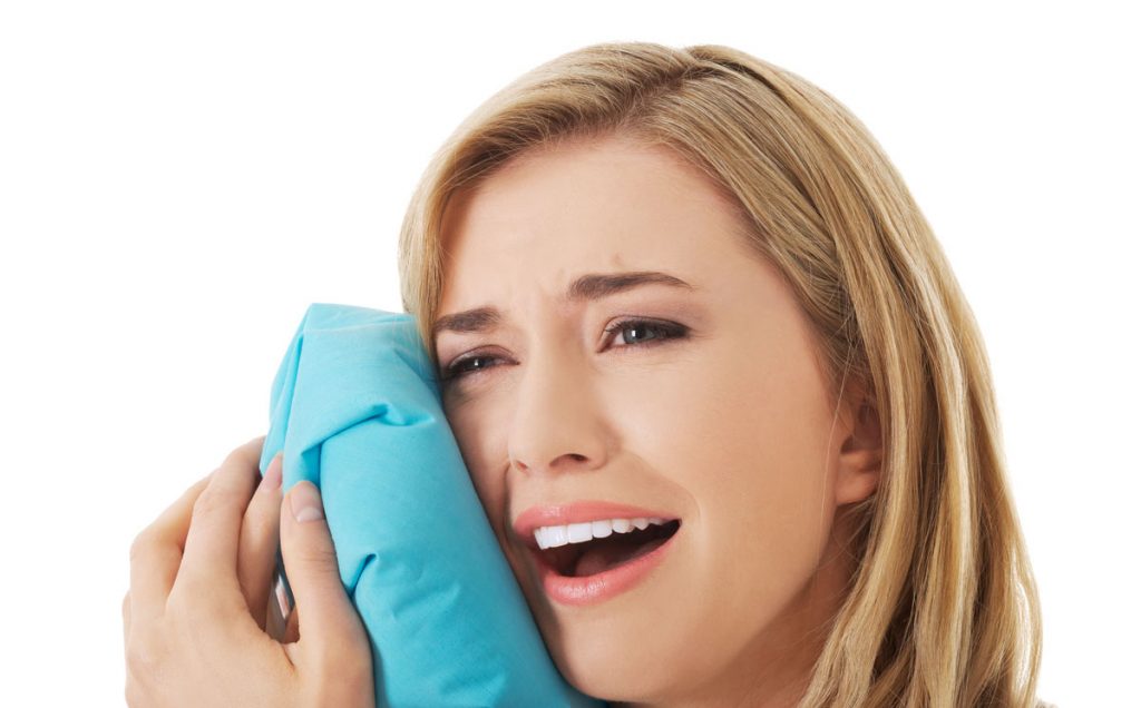 Woman experiencing tooth ache, holding ice bag