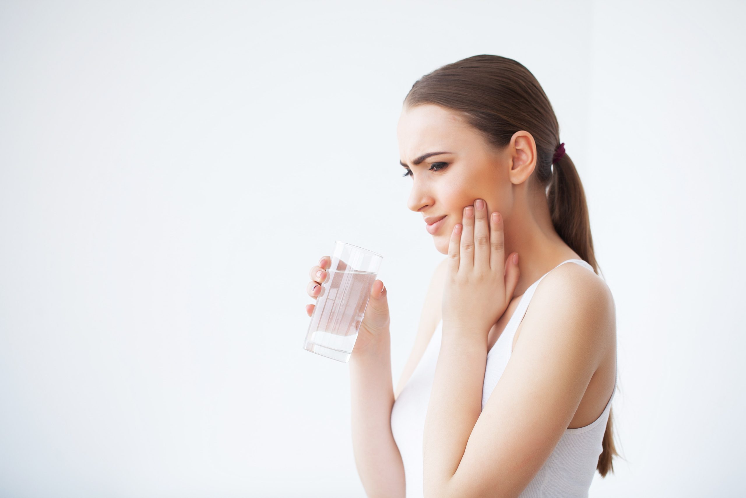 woman drinking a glass of water to deal with teeth pain