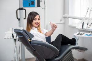 woman giving thumbs up in dentist's chair after having chipped teeth fixed