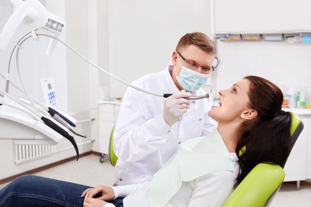 woman sitting in dentist's chair as man fixes her chipped teeth