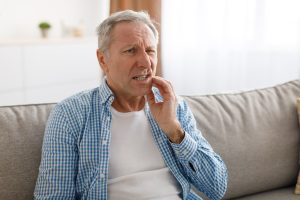 man sitting on couch with a dental injury