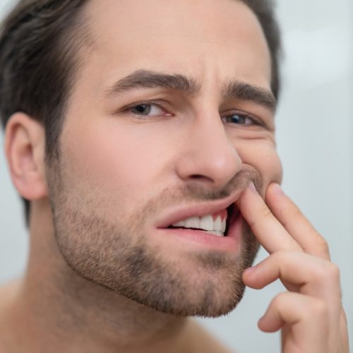 Dental problems. Man checking his teeth and looking disturbed